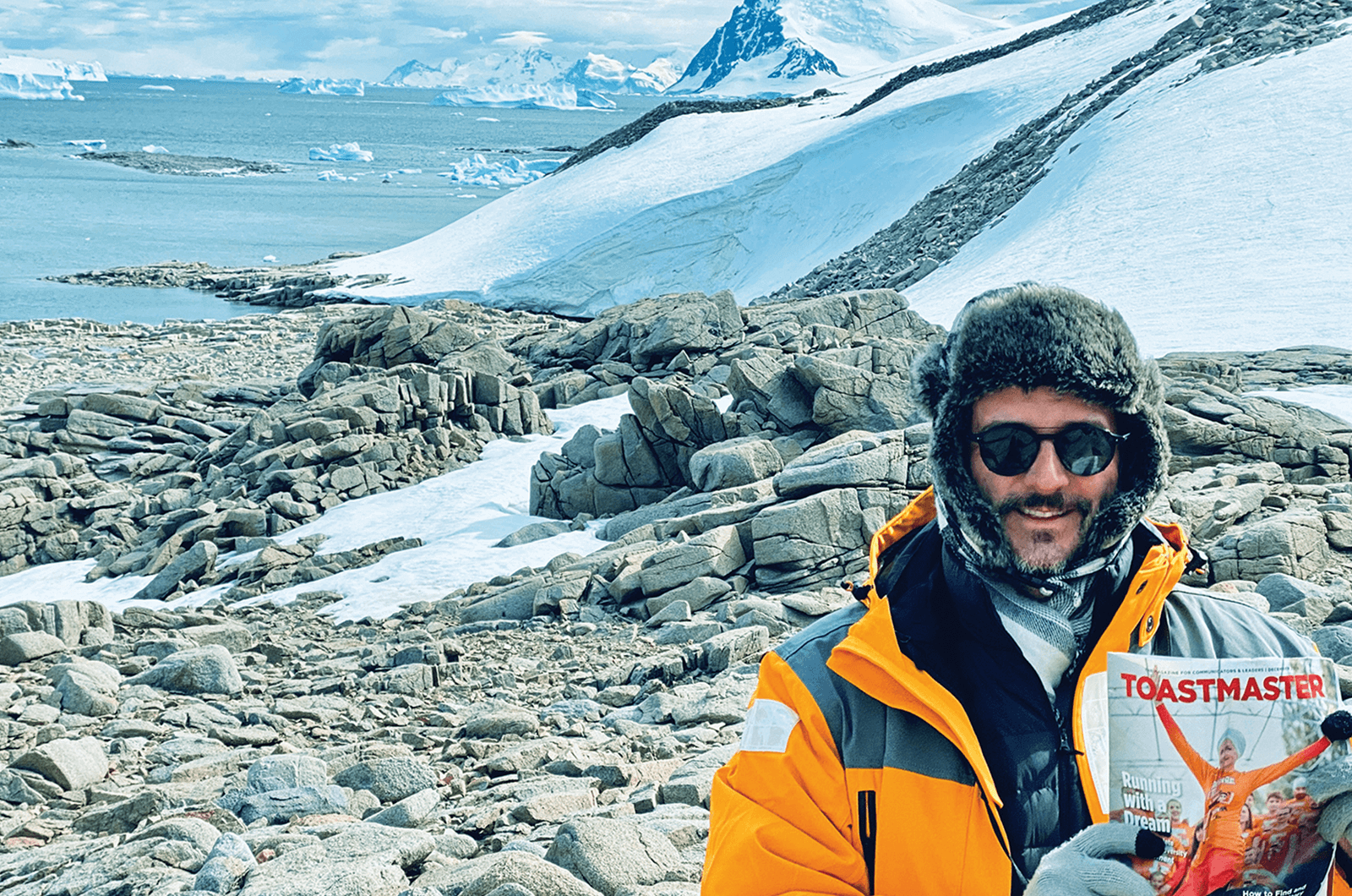 David Fraquelli of Los Angeles, California, U.S., explores Antarctica with his Toastmaster magazine in hand. 