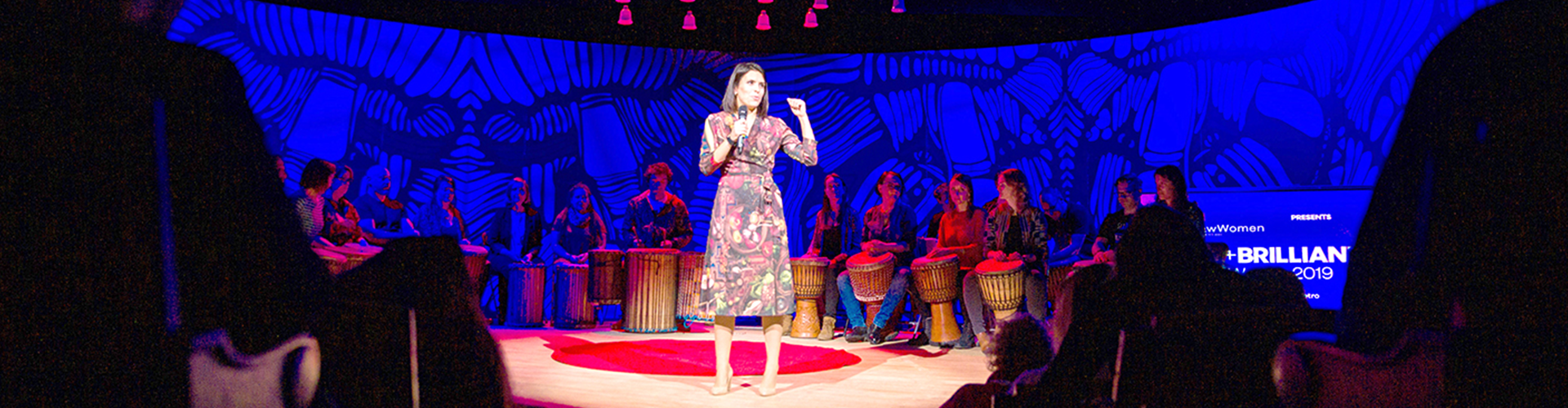 Elena Paweta giving speech on red dot on TEDx stage 