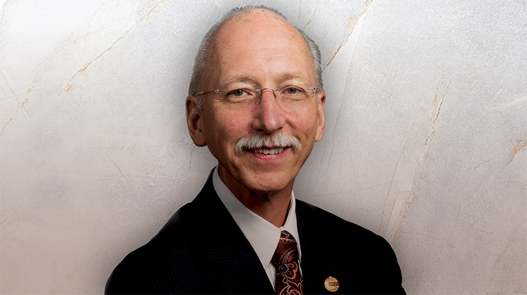 Toastmasters International President Richard Peck posing in suit and tie.