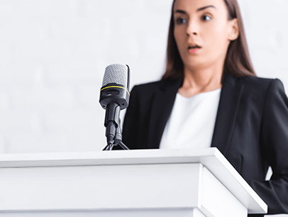 Woman standing at lectern looking scared