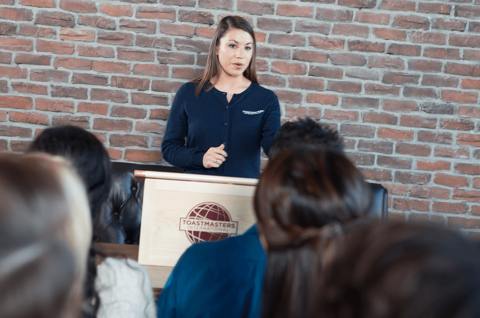 Woman in blue sweater speaking to group from lectern