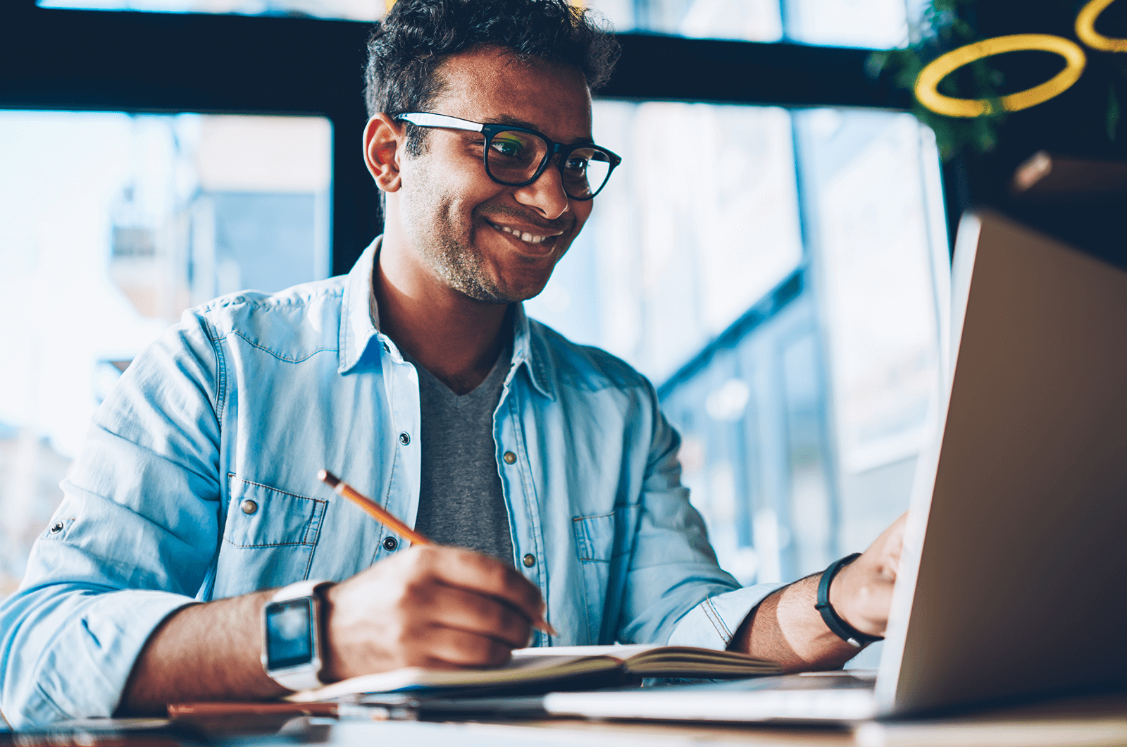 Man taking notes while looking at laptop