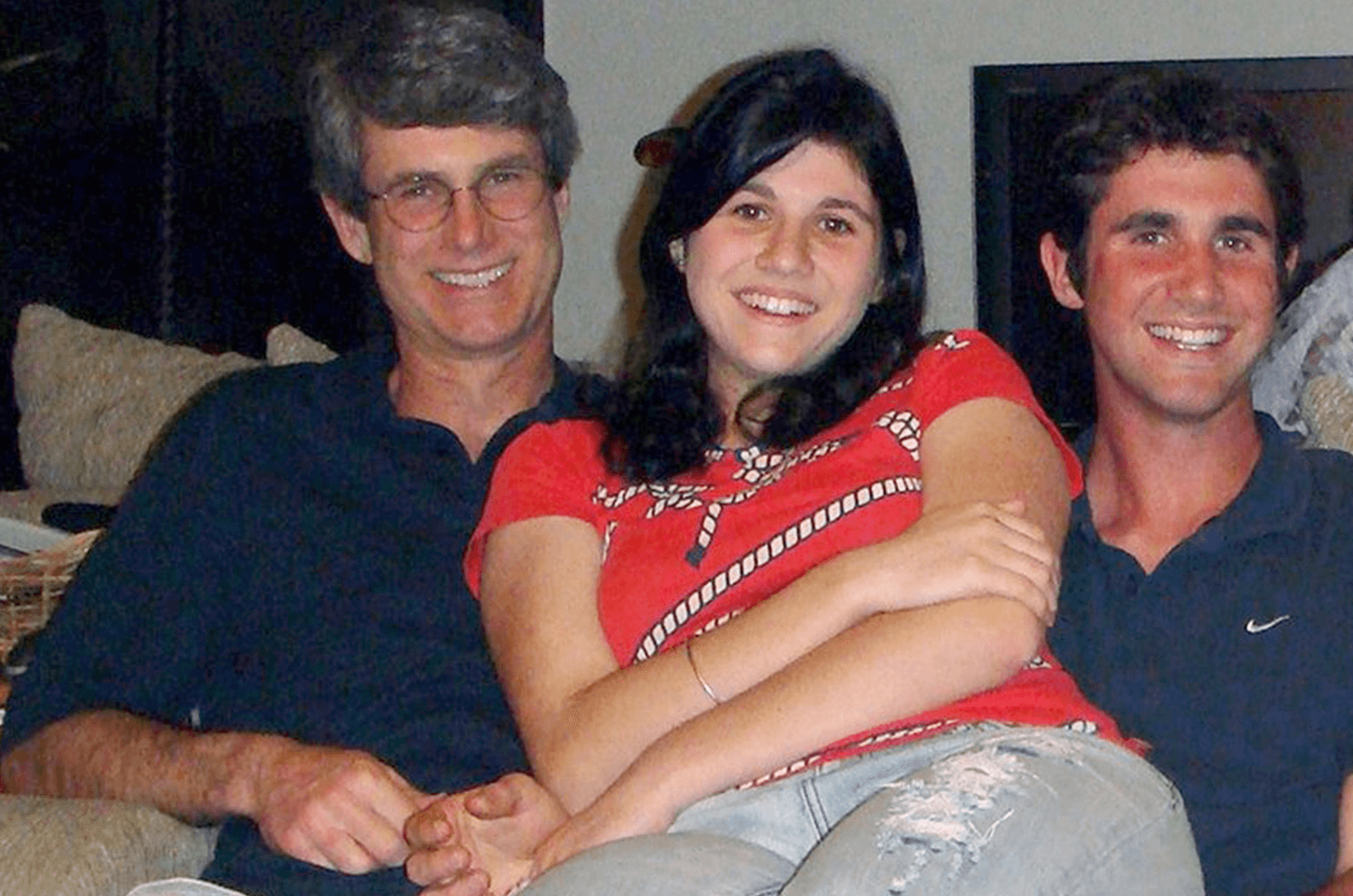 A father posing on couch with male and female adult children