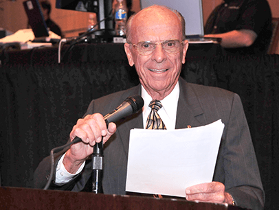 Don Ensch holding microphone and papers