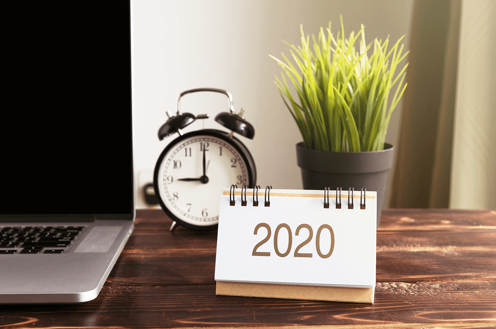 Desk with laptop, clock, calendar, and plant 