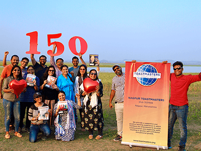 Group of people posing outdoors with banner and cut out numbers 150