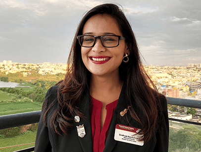 Woman posing outdoors in black jacket with pins