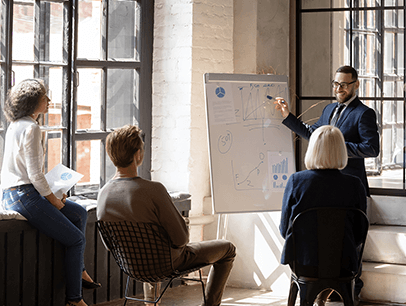 Man pointing to whiteboard for group of people 
