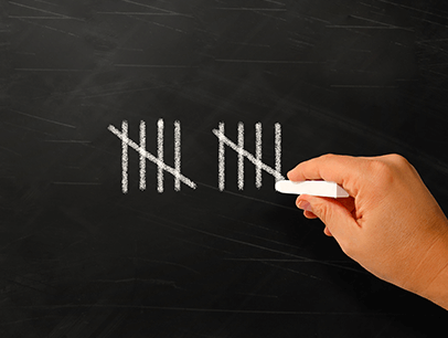 A hand writing numerals with chalk on blackboard 