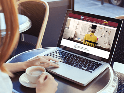 Woman holding coffee while reading on laptop