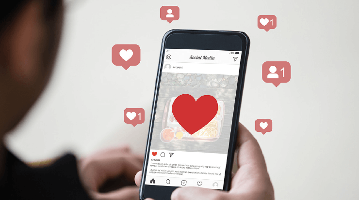 Social media hearts and thumbs up next to someone on smartphone