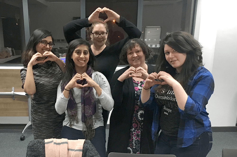Tanya (far right) makes a heart shape with her hands with fellow members at a club meeting.
