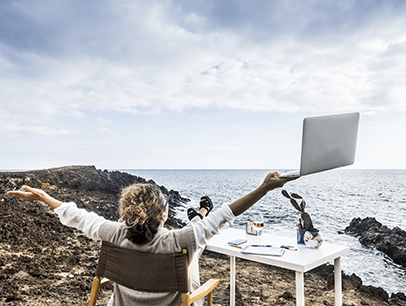 Woman holding laptop on beach looking at ocean 