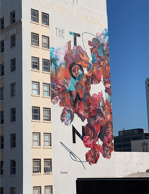 This artwork is called “The Town” and is painted on a building in Oakland, California.