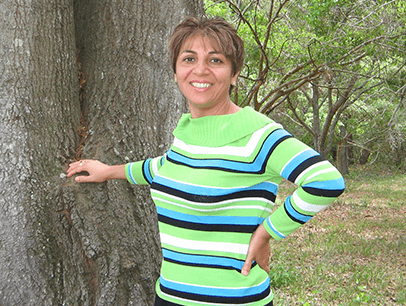 Woman in green sweater posing by tree