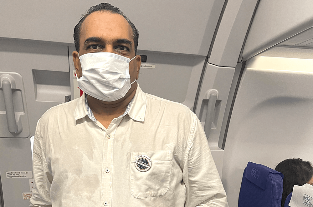 Nishant Mehta, DTM, of Mumbai, Maharashtra, India, wears his “Ask Me About Toastmasters International” button on a flight.
