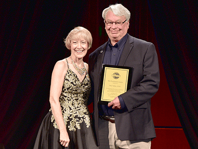 Man and woman posing with award