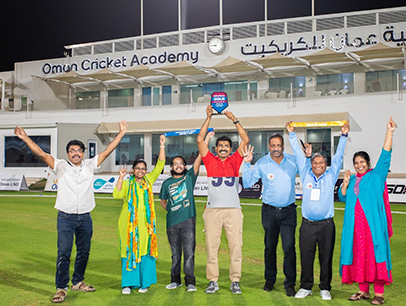 Group posing on cricket field with awards