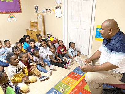 Man reading book to group of children