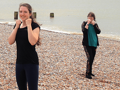 Two women on beach posing in fighter stance