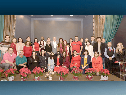 Group of people posing indoors with poinsettias up front 