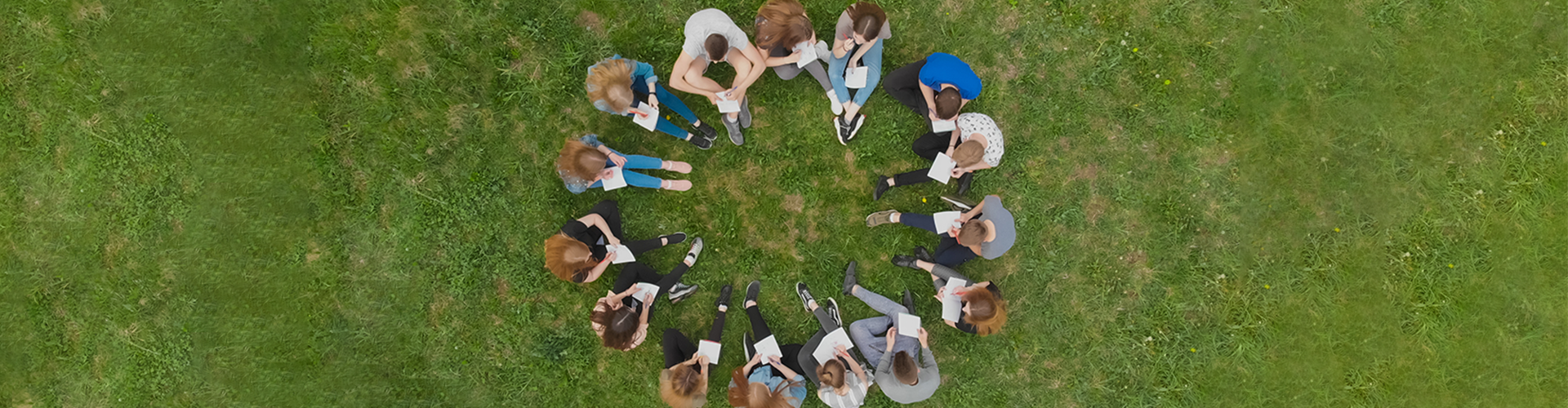 Group of people sitting in circle in grass
