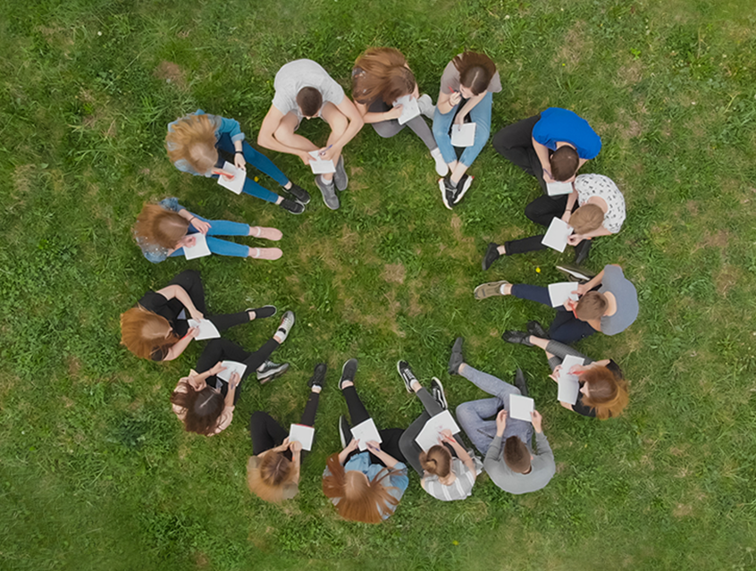 Group of people sitting in circle in grass